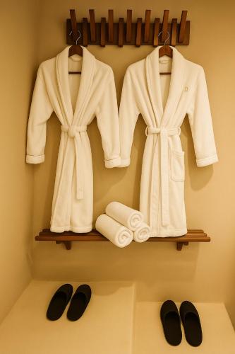 two white coats and towels on a shelf at Maison Maneki Tiny House Insolite 2 personnes avec Spa extérieur privatif in Lapoutroie