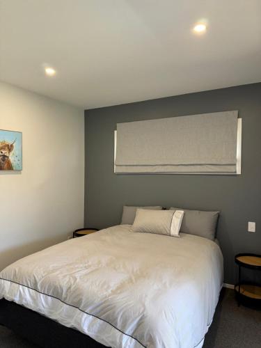 Un dormitorio con una cama blanca y una ventana. en Private self contained unit, en Pukekohe East