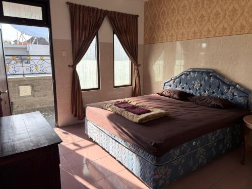 a bedroom with a bed with a blue head board at Cempaka 2 Homestay in Legian