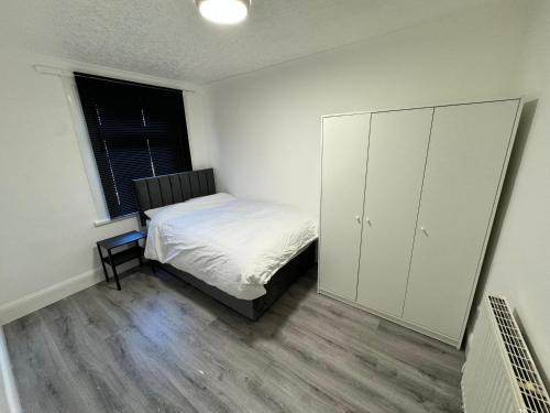 a bedroom with a bed and a cabinet and a window at Charming 3 Bed Home Stay in Plumstead