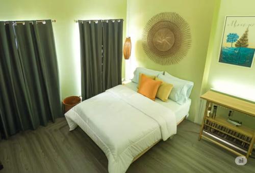 a bedroom with a white bed with orange pillows at Urban Zen - Family Condo with Parking in Nuvali in Calamba