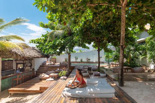 a woman sitting on a pillow under a tree at Dar Mar Hostel & Coworking in Paje