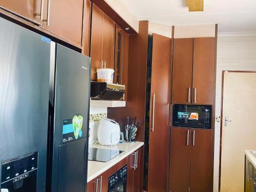 a kitchen with a stainless steel refrigerator and wooden cabinets at Inocova Fly in Kempton Park