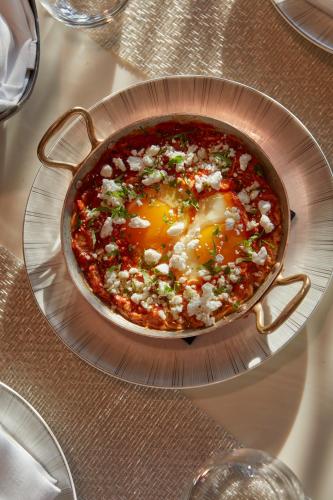 a pizza in a pan with an egg on a table at Mandarin Oriental, Doha in Doha