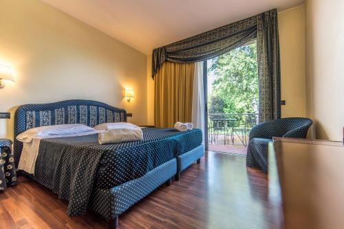 a bedroom with a bed and a large window at Yachting Hotel Mistral in Sirmione