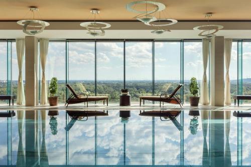 a room with a pool with chairs and windows at Grand Hotel River Park, a Luxury Collection Hotel, Bratislava in Bratislava