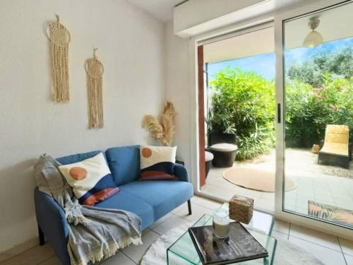 a living room with a blue couch and a glass table at Le Cocon - 5 min to Monaco - Ideal couple or business - Near events - Terrace and balcony - Premium services - Extra parking in Fontvieille