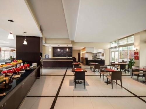 a restaurant with tables and chairs and a cafeteria at ibis Muscat in Muscat