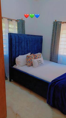 a bed with a blue headboard in a room at Zion Apartment Diani in Diani Beach
