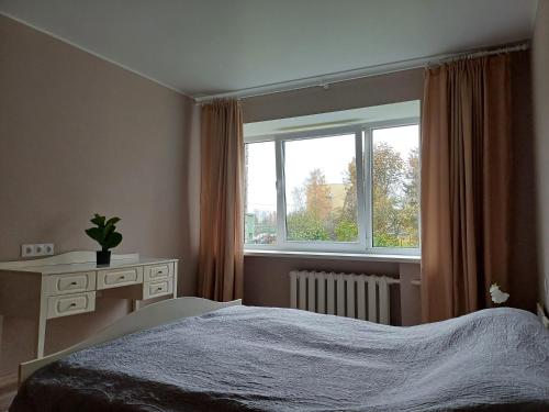Un dormitorio con una cama y un escritorio y una ventana. en Narva mnt 26, en Jõhvi
