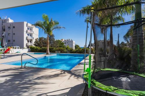 a swing by a swimming pool with palm trees at Pearl Beach Luxury Family Suite in Limassol