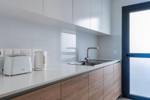 Pearl Beach Luxury Family Suite في ليماسول: مطبخ أبيض مع حوض ومكتب