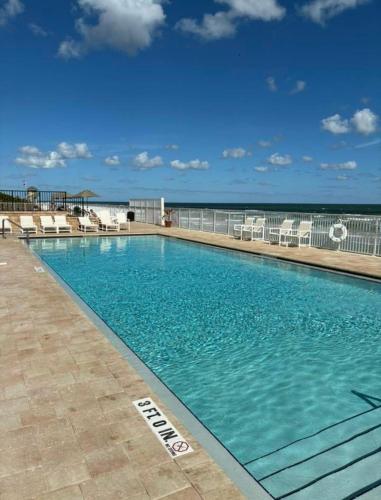 a swimming pool with chairs and the ocean in the background at Oversized condo Beach Oasis 601 Gorgeous Ocean front with spectacular views in Daytona Beach