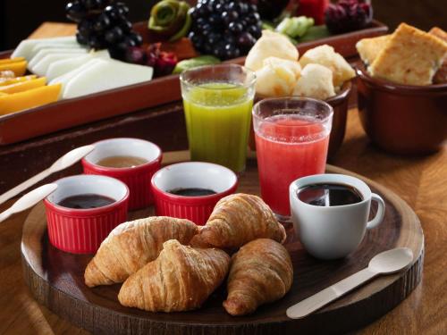 a tray of food with croissants and drinks on a table at Mercure Maceio Pajuçara in Maceió