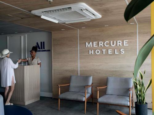 a woman standing at a counter in a hotel lobby at Mercure Maceio Pajuçara in Maceió