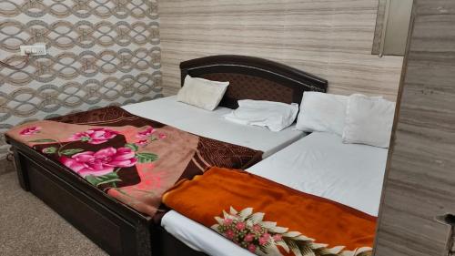 two beds in a room with flowers on them at Guru Kripa Dham in Vrindāvan