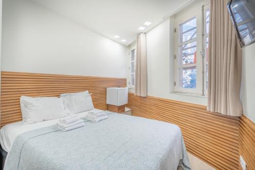 a bedroom with a bed with white sheets and a window at Souto Centro Rooms in Braga