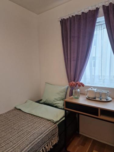 a bedroom with a bed and a window with purple curtains at Nordstay Tromso in Tromsø