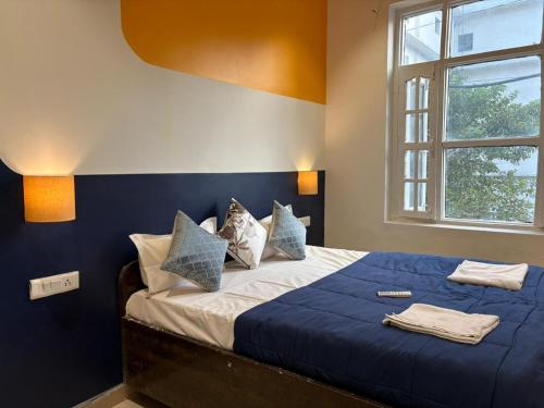 Un dormitorio con una cama con sábanas azules y una ventana. en Joey's Homestay, en Rishīkesh