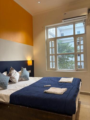 a bedroom with a bed with blue sheets and a window at Joey's Homestay in Rishīkesh
