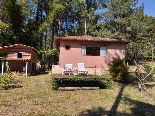 a small pink house with two chairs in the yard at Aconchego das Montanhas in Alagoa