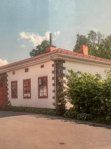a white building with red windows on a street at Superfin lägenhet 2 rok Söderfors wärdshus in Söderfors