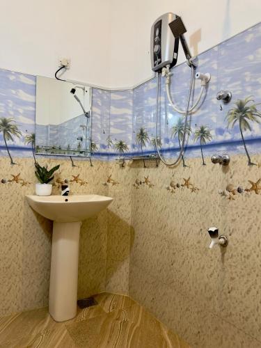 a bathroom with a sink and a shower with palm trees at Abheena - Weligama in Weligama