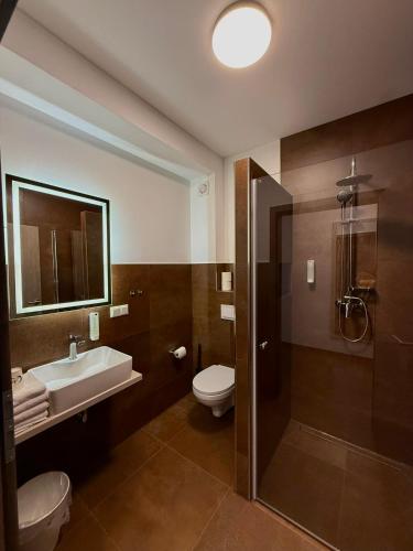 a bathroom with a toilet and a sink and a shower at Ayhan Hotel in Burgdorf