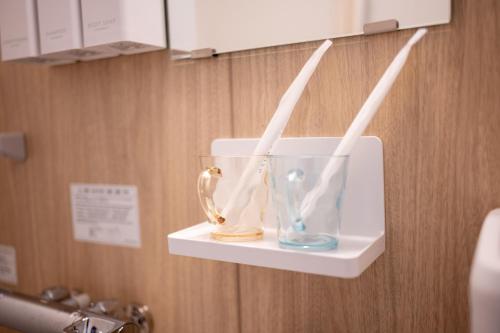 a shelf with a glass vase and two white straws at Home Story in Tokyo 江戸川区平井駅-上野 秋葉原まで直通 in Tokyo