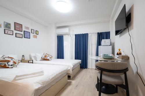 a bedroom with two beds and a table and a chair at Home Story in Tokyo 江戸川区平井駅-上野 秋葉原まで直通 in Tokyo
