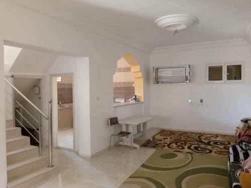 a white room with a staircase and a table in it at appartement Tozeur médina in Tozeur
