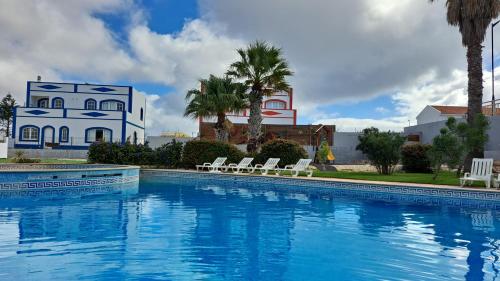 a large swimming pool with chairs and a house at Casa Papillon in Sagres