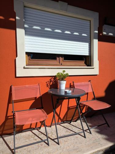 a table and two chairs and a window with a plant at Casa Tertúlia in Covão do Coelho