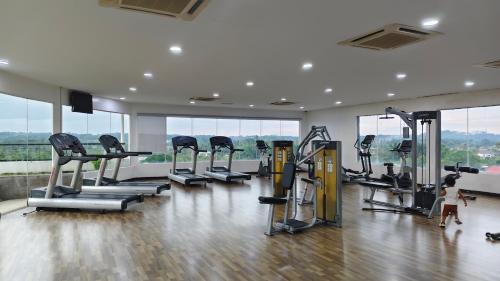 a gym with a row of treadmills and a little girl walking in front at MZS Studio Swiss Garden R in Kuantan