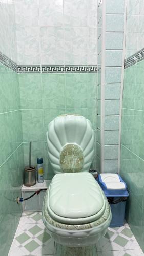a white toilet in a green tiled bathroom at MOK Apartment in Samarkand