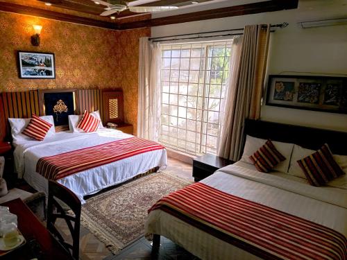 イスラマバードにあるCrosswinds Guest Houseのベッドが2つと窓があるホテルの部屋