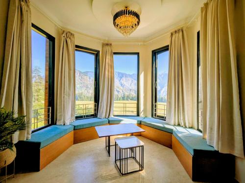 a living room with windows and a table and chairs at Heavenly Retreat, Shangarh in Shangarh