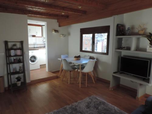 a living room with a table and chairs and a television at Casa La Muralla, reformada en Casco Antiguo in Cuenca