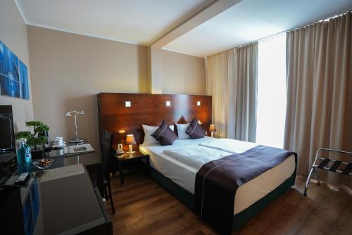 a bedroom with a bed with a desk and a window at Hotel Lumière an der Messe in Frankfurt/Main