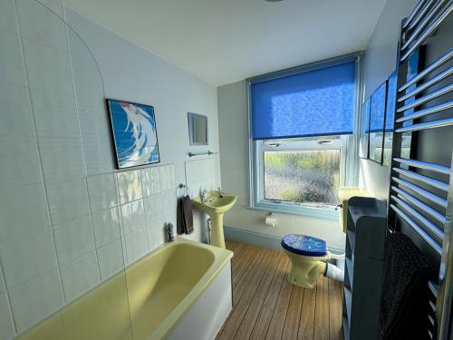 Un baño con una bañera amarilla y un lavabo. en Sea views at Carina centrally located in village, en Seaview
