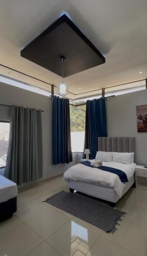 a bedroom with a large bed with blue curtains at Golden View Boutique Guesthouse in Windhoek