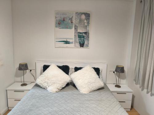 a bedroom with a bed with white pillows and two lamps at Apartamento nuevo con parking y piscina gratis in Fuengirola