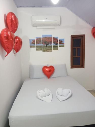 a bed with red balloons and a heart on the wall at Pousada do Sol in Pedra de Guaratiba