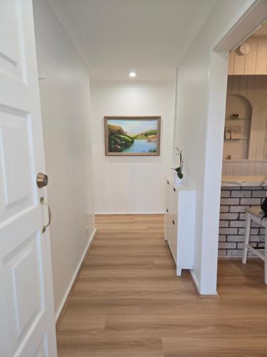 a hallway with white walls and a painting on the wall at The Greenview Luxe Home - Hornsby in Hornsby