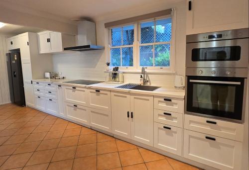 a kitchen with white cabinets and a stove top oven at The Greenview Luxe Home - Hornsby in Hornsby