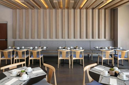 Un comedor con mesas y sillas y una pared. en City Express Plus by Marriott Ciudad de México Mundo E, en Ciudad de México