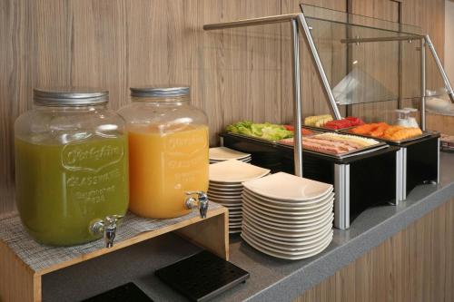 Un buffet con dos jarras de jugo y platos de comida. en City Express Plus by Marriott Ciudad de México Mundo E, en Ciudad de México