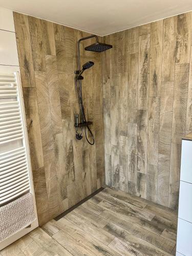 a shower in a bathroom with a wooden wall at Komfortzimmer in Trieben