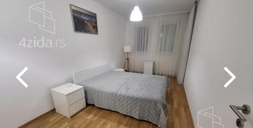 una camera da letto con un letto in una stanza bianca di Stan a Zrenjanin