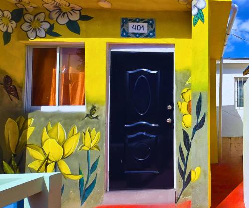 une maison avec une porte noire avec des fleurs peintes dessus dans l'établissement Sunbeha Resort, à Juan Dolio